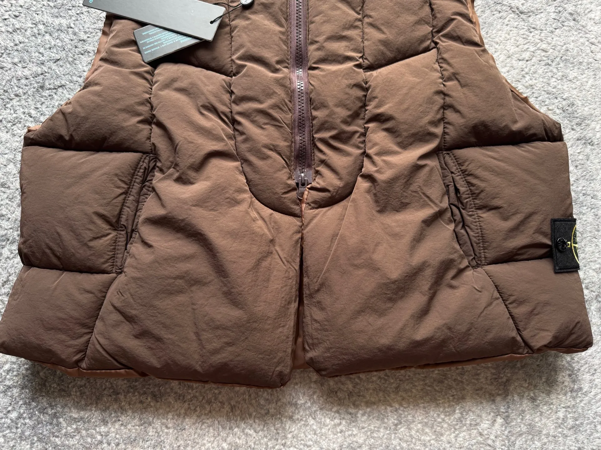 P280 Stone Island 25Fw Stone Island Linear Split Silhouette Cotton-Filled Deconstructed Waistcoat Jacket Stone Island's 2025 Grand Offering The outer layer is made of high-quality wrinkled nylon fabric, and the inner layer is filled with high-comfort and warm velvet cotton. The filling amount is very sufficient and the overall clothing is very full. The upper body silhouette and warmth are well guaranteed. The front and rear split line design is simple without losing details. The double zipper puller zipper increases practicality. The short design is very suitable for trendy matching in all seasons. It is very effective whether it is paired with a sweatshirt or a jacket. The basic black and chocolate brown meet the requirements of jumping in color and being versatile. It is a powerful tool for matching lazy suits when going out on the street. The classic emblem armband of Stone Island highlights the brand tension. It is first released on the entire network. Manufactured by a large factory. Complete with three-label accessories. Same style for men and women. Color: brown/black Size: m～xl